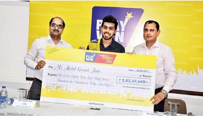 A photo of Akshit Kumar Jain holding a cheque for winning the lottery